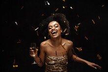 Happy african american woman in party dress drinking champagne
