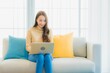 © siraphol - Portrait beautiful young asian woman use computer laptop on sofa decoration interior