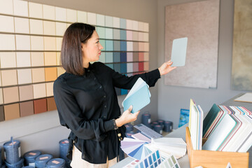 Young woman choosing materials for home renovation. interior designer looking at color samples for wal. House renovation concept
