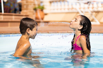 Two friends spitting water from mouth in a pool