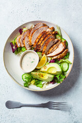 Canvas Print - Grilled chicken salad with avocado, cucumber and dressing, top view. Healthy food concept.