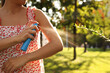 © New Africa - Woman applying insect repellent onto hand in park, closeup. Space for text