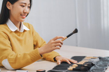 Asian professional make-up artist working at beauty salon blending eyeshadow on face of a female client