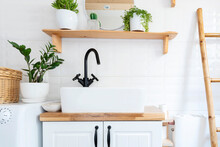 Small Bathroom In Rural Style In A Cottage With White Tiles, Modern Basin, Tap And Wooden Cabin And Shelf. Stylish Interior With Plants And Round Mirror In Vintage Style. 
