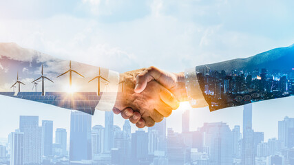 Concept of collaboration to change the world to reduce global warming,energy sources for renewable,sustainability by alternative energy.Double exposure of handshake of wind turbine and night city.