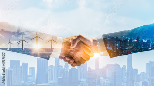 Concept of collaboration to change the world to reduce global warming,energy sources for renewable,sustainability by alternative energy.Double exposure of handshake of wind turbine and night city.
