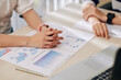 © DragonImages - Hands of business people sitting at table with charts and reports and discussing business development