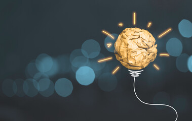 Wall Mural - Scrap yellow paper ball with drawing glowing light and wire harness which sign of lightbulb on blue bokeh background, creative thinking idea and innovation concept.