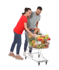 Poster - Happy couple with shopping cart full of groceries on white background