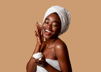 beautiful young african american woman applying cream on face