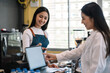© amnaj - Image of a customer ordering coffee through a tablet at the coffee shop.