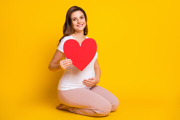 Poster - Photo of sweet pretty woman expecting child wear white outfit hugging belly holding red heart isolated yellow color background