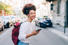 Young Woman In Street Holding Phone And Smiling