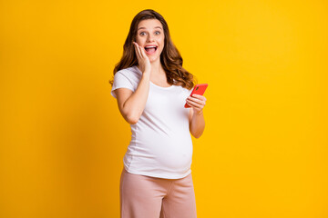 Poster - Portrait of pretty amazed cheery pregnant girl using gadget fast speed 5g notification isolated over bright yellow color background