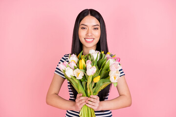 Wall Mural - Photo portrait of brunette girl smiling happy received tulips bunch isolated on pastel pink color background