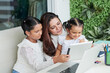 © DragonImages - Cheerful mother and two girls sitting at table in backyard and watching animated movie on tablet computer