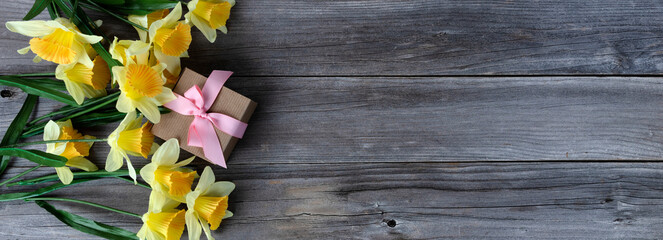 Sticker - Top view of a gift box with yellow daffodil on weathered wooden planks for Mothers day love holiday