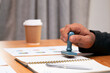 © Meng_Dakara - Close up Asian businessman holding rubber stamp and stamping with approved stamp on document. Finance business concept