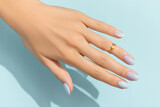 Womans hands with trendy manicure on blue background. Summer nail design