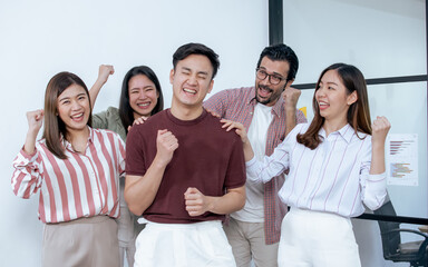 Asian young man and his colleagues are smiling and very happy on their success