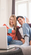© DMegias - Young couple chatting with friends or family on a video call with their laptop while staying at home.