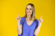 Portrait of beautiful young woman pointing up over yellow background.