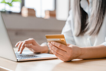 Close up shot of a credit card in woman`s hands with laptop for online shopping