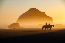 Face Rock, With Horses And Riders,  At Sunset On The Southern Oregon Coast At Bandon