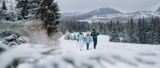 Wall Mural - Family with small daughter on a walk outdoors in winter nature, Tatra mountains Slovakia.