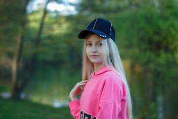 portrait of a teenage girl with blond hair in the background of a lake in a park. high quality