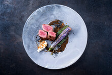 Modern Style Traditional Wild Hare Back Filet Braised With Baby Eggplant And Quenelles In Game Jus Served As Top View On A Design Plate With Copy Space
