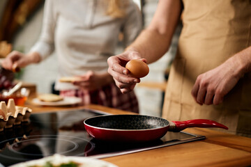 Close-up of man preparing eggs in the kitchen.