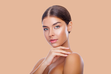 Beautiful Portrait Of Young Woman. Advertisement. Perfect Skin Face, Girl Touches her Face with her Hands. Makeup. Healthy Fresh Skin. Beauty. Peach Background. Isolated.  