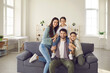 © Studio Romantic - Portrait of happy young family with kids at home. Cheerful mother, father and little children smiling and looking at camera, sitting on sofa in the living-room of their new house or apartment