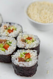 Fototapeta Londyn - Sushi rolls prepared by professional asian chef with traditional Japanese ingredients. Salmon, rice, vegetables, sesame seeds. Sushi cooking and making concept