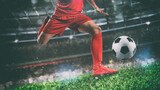 Fototapeta Sport - Close up of a soccer scene at night match with player in a red uniform kicking the ball with power