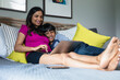 © Gerald Carter/Creative Flame - Indian mother and son snuggles in bed while mom is working on laptop