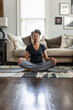 © Gerald Carter/Creative Flame - Black mom meditates in family room, teenage son on phone in background, peaceful health  and wellness