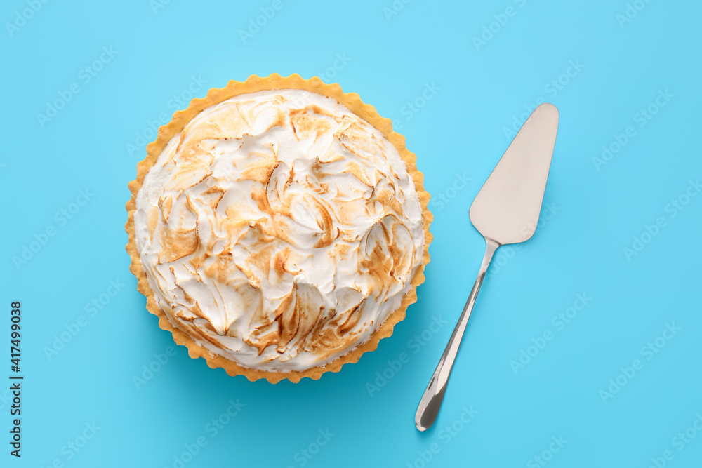 Tasty coconut pie and spatula on color background