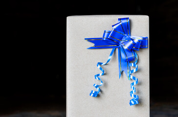 Gift wrap with blue bow on a black background.