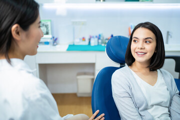 Wall Mural - Caucasian girl consulting Asian female dentist about oral care checkup