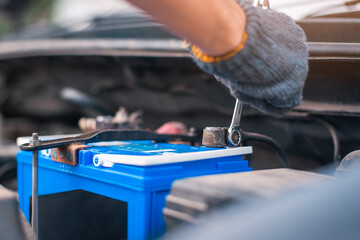 Wall Mural - a man tightens with a wrench bolts for fastening a new battery, installing spare parts for a car