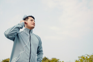 Wall Mural - Young sportman jogging and listening music in the park.