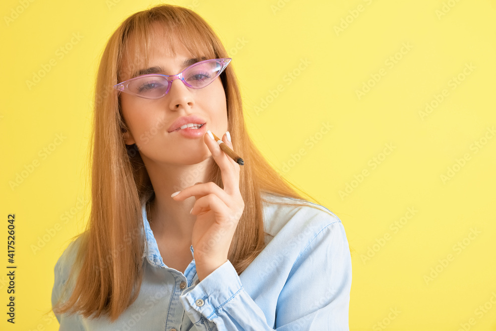 Young woman with cigarette on color background