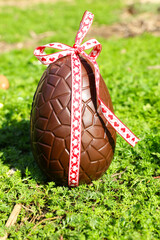 chocolate easter egg with ribbon in the garden