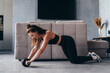 © undrey - Fit woman working out with ab exercise wheel at home.