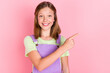 Photo portrait of schoolgirl pointing finger advising copyspace isolated on pastel pink color background