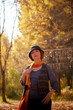 © keleny - Mature woman in interesting dress and long orange scarf in autumn park and trees with yellow leaves background