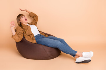 Poster - Full size profile photo of blond optimistic lady lie down on bag wear shirt jeans sneakers isolated on beige color background