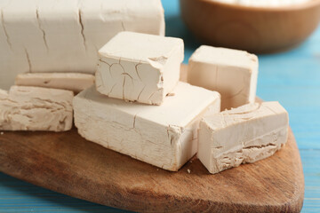 Pieces of compressed yeast on wooden board, closeup